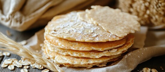 Poster - Oatmeal pancakes stacked elegantly with a sprinkle of flour on a rustic wooden background showcasing healthy breakfast options.
