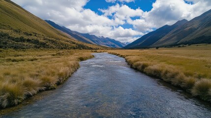 Aufkleber - Scenic mountain stream flowing through lush valleys under a cloudy blue sky in a serene natural landscape.