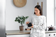 © Pixel-Shot - Beautiful young happy woman with wireless portable speaker in kitchen at home