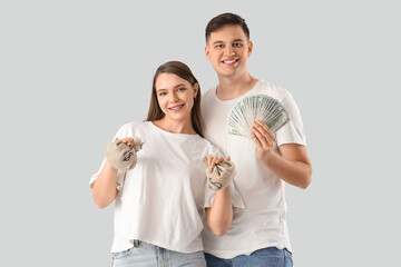 Wall Mural - Young couple with money and sack bags on light background