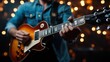 © Dulemegapixel - Musician skillfully strums a guitar under warm golden stage lighting, creating a rich and passionate ambiance that captivates the audience in the performance.