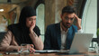 © Yuliia - Business colleagues Arabian man muslim woman in hijab bank payment laptop count bills check invoice financial problem account debt bankruptcy upset frustrated stressed businesswoman businessman office