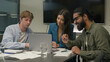 © Yuliia - Company teamwork at office desk talk planning discuss online project laptop multiethnic business team men women colleagues male female Indian Caucasian Arabian businessmen businesswoman corporate work