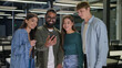 © Yuliia - Diverse multiracial business people women men students group friends look screen mobile phone happy cheerful smiling businessmen businesswomen using smartphone in office discuss good news team project
