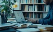 © EFA - A person working on a laptop surrounded by books and stationery in a study.