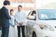 © buritora - 自動車購入・査定・買取にきた夫婦と接客するセールスマンの若いアジア人男性