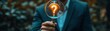 © Itsaree  - business man holding magnifying glass, glowing lightbulb with question mark, idea and innovation concept, focus on creativity, copy space for message