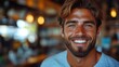 © emkos - Happy young man smiling at camera in cafe.