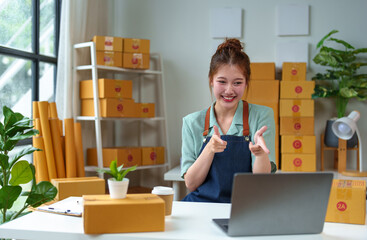 Startup, small business, SME owner, female entrepreneur working to pack parcels, showing happy expression, business success. Good feedback from customers independent business idea.