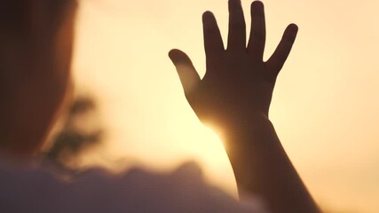 Canvas Print - silhouette of hand of girl child in sun glare. faith in god religion concept. close up hand child girl fingers silhouette at sunset sun glare in nature. dreams religion future concept lifestyle