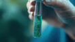 © pisan thailand - A hand holds a test tube containing a vibrant green liquid, suggesting a scientific or experimental context.