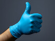 © Wittawit - Male hand in blue glove giving confident thumbs up gesture
