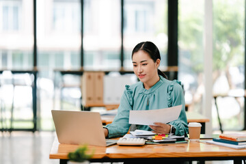 Wall Mural - Young Asian woman doing financial accounting and taxes for a company Organizing account analysis reports Investment information Financial and tax system concepts