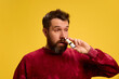 © Lustre Art Group  - Young man with runny nose, suffers from allergy, spraying it to remove symptom against yellow studio background. Concept of healthcare, medicine, infection and treatment. Ad.