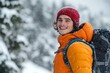 © ChaoticMind - A man with a warm smile and wearing an orange jacket enjoys the wintry snowfall, conveying happiness and warmth despite the cold in a snowy landscape.