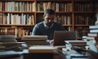 © EFA - A man working intently on a laptop surrounded by stacks of books.
