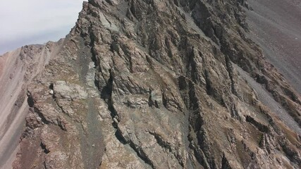 Wall Mural - Diving on a FPV drone along the steep cliffs in the gorge. The sun's rays are coming out from behind the peak. Big rocks, green grass and a river runs down the gorge. Flying down among the mountains