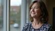 © Kenny - Mature caucasian woman smiling by window in thoughtful moment