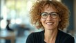 © EFA - A smiling woman with curly hair and glasses in a bright, modern setting.