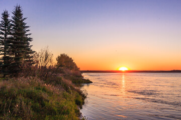 Wall Mural - a beautiful sunset over a lake with a tree in the background