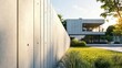 © Suphawan - A tall prefab concrete fence with a beveled edge design, shielding a luxury villa from outside view.