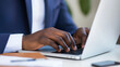© Helga - A man in a professional environment deeply engaged in work on his laptop. Perfect for content on efficiency in the workplace, time management techniques, business technology, and o