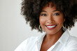© hkjdesign - A smiling Black woman with an afro hairstyle  wearing a white shirt and gold hoop earrings.
