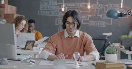 Asian businessman working with computer typing at desk in creative coworking office. Professional occupation and modern technology concept.