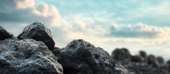 Poster - Textured Black Rocks Against a Blurred Sky with Light Clouds Ideal for Background and Text Overlay in Nature or Landscape Themes
