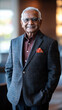 © Anastasia - A senior Indian man stands confidently in a stylish blazer and shirt, showcasing a warm smile and a vibrant pocket square in a modern indoor setting