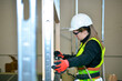 © pacoocimage - Construction worker mounting plasterboard with spirit level on metal frame