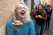 © Halina Berah - A group of multiracial friends having a good time eating and drinking vegan food on a patio, with attention drawn to the center girl's face.