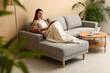 © Pixel-Shot - Young woman reading book on sofa in stylish living room