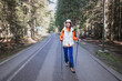 © EdNurg - Hiker walking on a paved road in a coniferous forest, enjoying a sunny day
