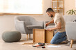 © Pixel-Shot - Young man with screwdriver assembling wooden table at home