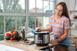 © Pixel-Shot - Young woman with multi cooker on table in kitchen