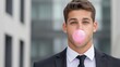 Young businessman in suit blowing bubble gum outdoors