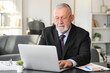© Pixel-Shot - Senior businessman working with laptop at table in office