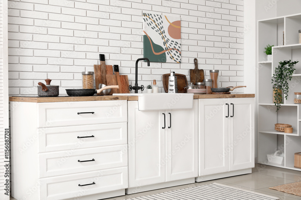 Shelving unit and kitchen counter with utensils near white brick wall