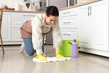 Wall Mural - Young woman wiping floor in kitchen