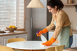 © Pixel-Shot - Young woman cleaning dining table in kitchen
