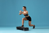 Woman in gym clothes doing exercise with step platform on light blue background