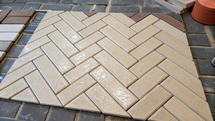 Aufkleber - Tiles in a herringbone pattern with one section almost complete highlighting drops of adhesive and the careful placement of a tile ter nearby.