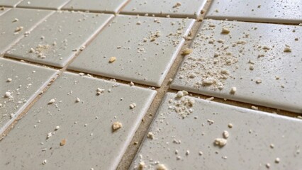 Aufkleber - A closeup of partially removed adhesive residue on the back of a tile with small flecks of removed grout tered around revealing the remnants of its past installation.