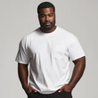 © Anastasiia Havelia - In an e-commerce shoot of a plus-size model, an African-American man wearing a white T-shirt and black pants confidently faces the camera, with a clean light gray shirt in the b