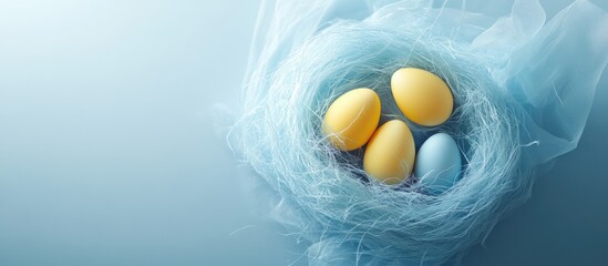 Wall Mural - Pastel yellow and blue Easter eggs nestled in a soft blue napkin nest on a tranquil background with ample copy space for marketing use