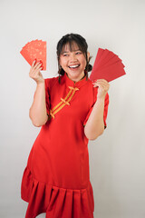 Smiling young asian woman wearing red traditional chinese dress is holding many red envelopes, isolated over white background. Concept for Lunar New Year Party.