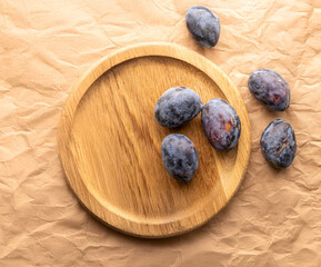 Wall Mural - Generated Image. Black ripe plums with household utensils on a wooden table, close-up, top view.