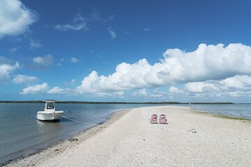 Poster - Serene beach scene with boat and blue sky.