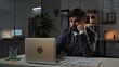 © kinomaster - Adult business man manager sitting at desk working on laptop in office overtime in evening, typing doing research, reading data, tired bored expression.